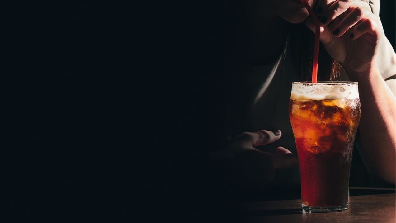 a picture of a cola glass and a woman drinking from a red straw