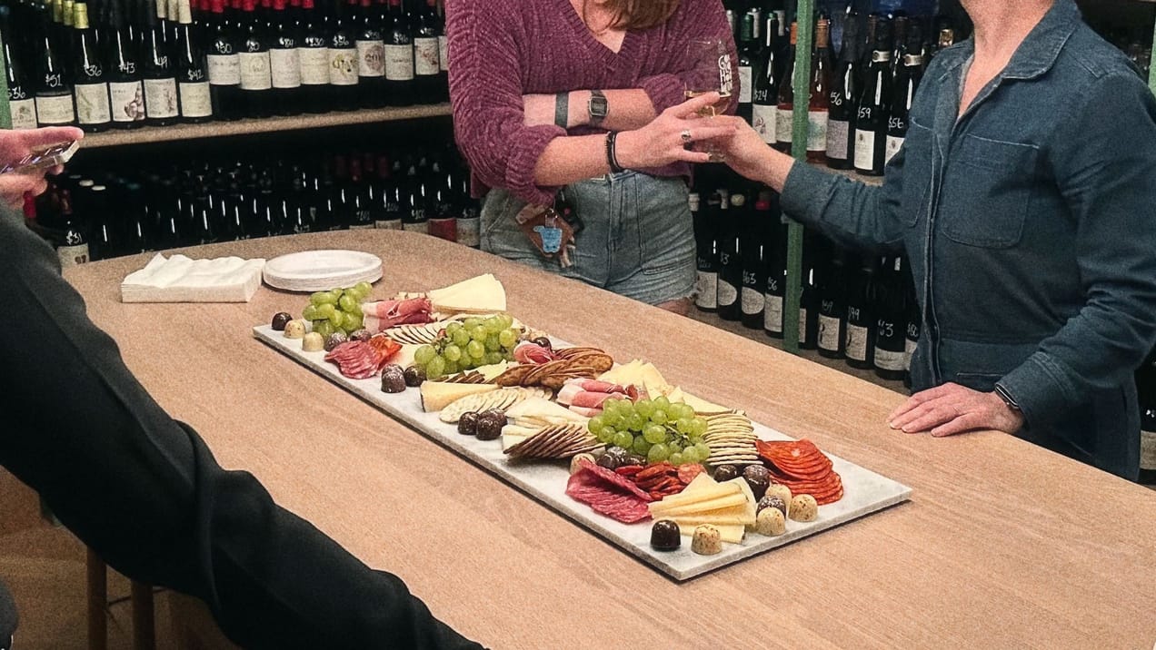cheese, crackers, smoked meats, grapes and chocolates served over marble tiles.