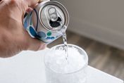 picture of a can pouring out sparkling water into a glass with crushed ice