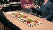 cheese, crackers, smoked meats, grapes and chocolates served over marble tiles.